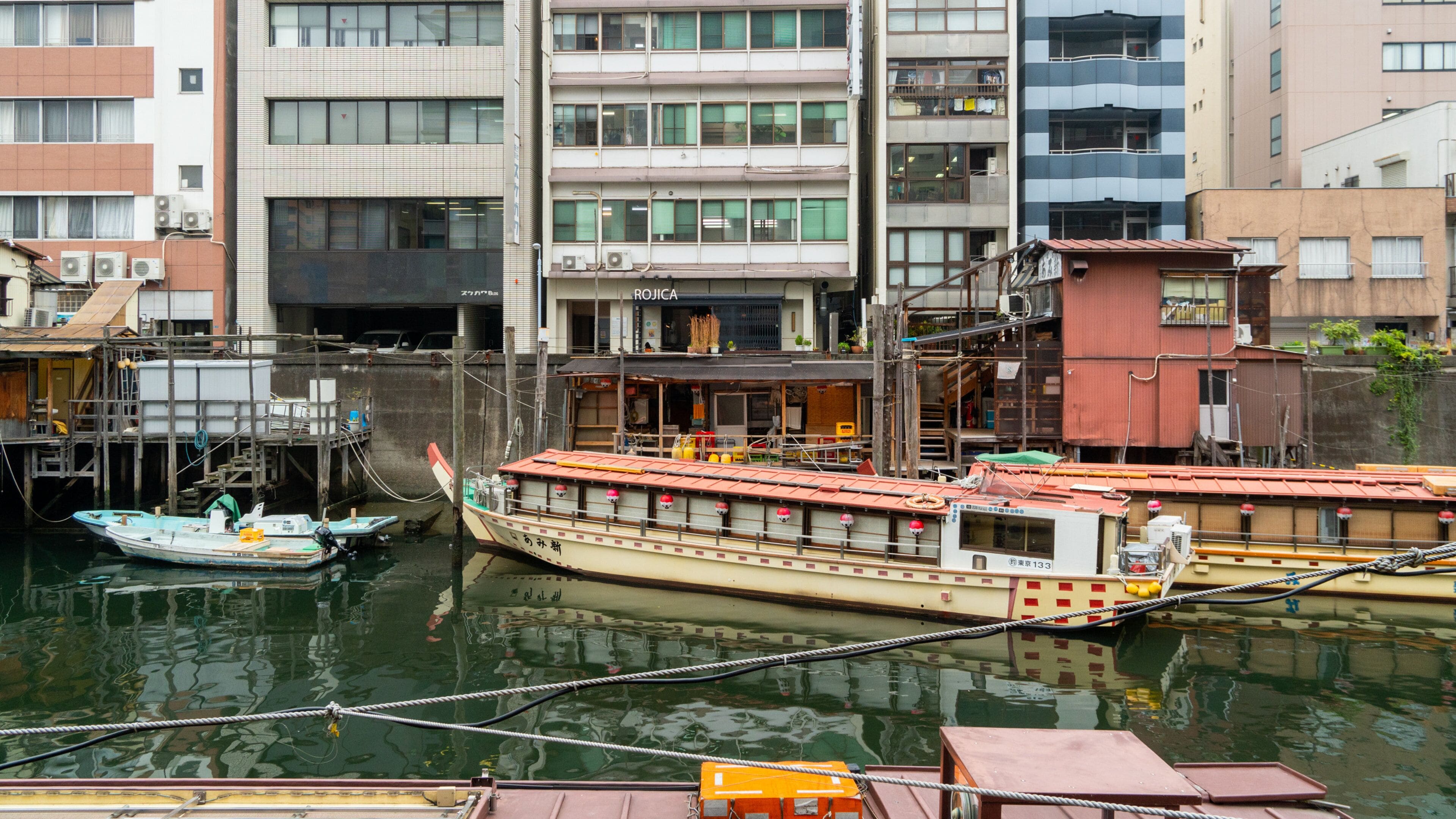 A traditional boat docked at a pier with buildings in the background.