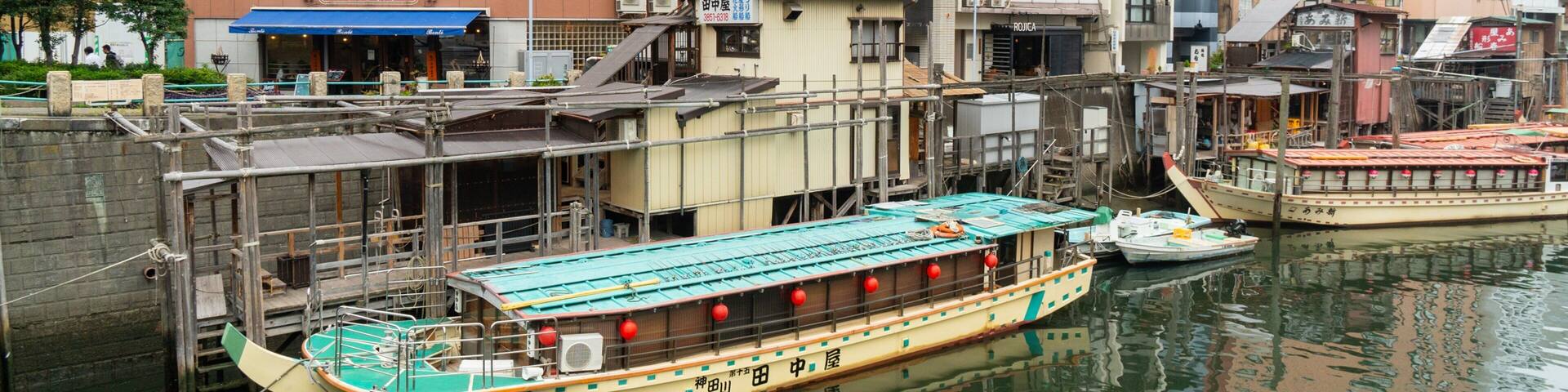 A river with boats docked, surrounded by buildings including a hotel and a restaurant.