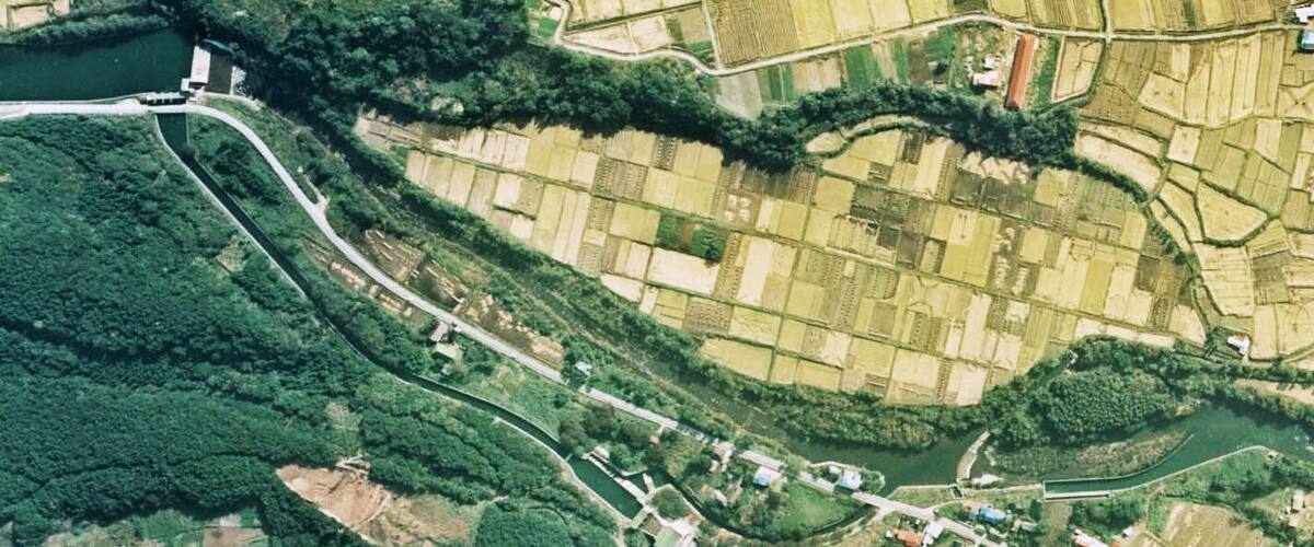 An aerial view of a rural landscape with fields, a river, and a small village.
