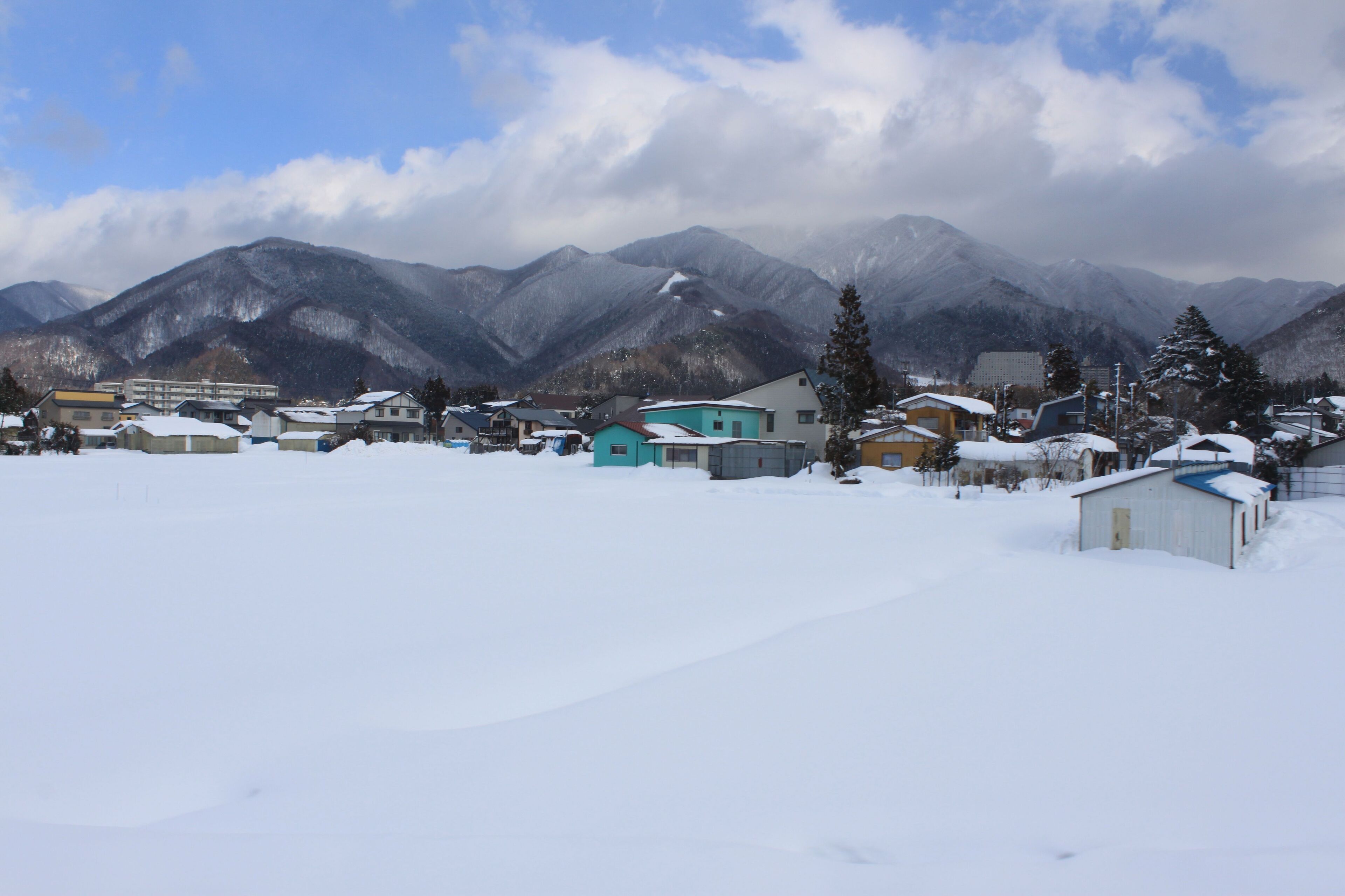 A snow-covered village with houses and mountains in the background.