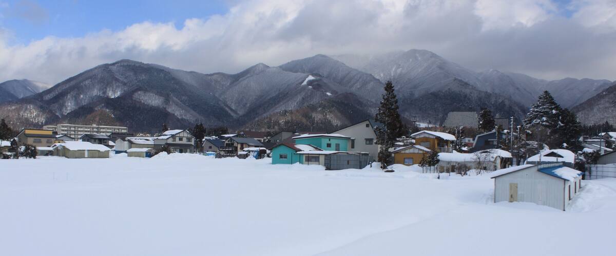 A snow-covered village with houses and mountains in the background.