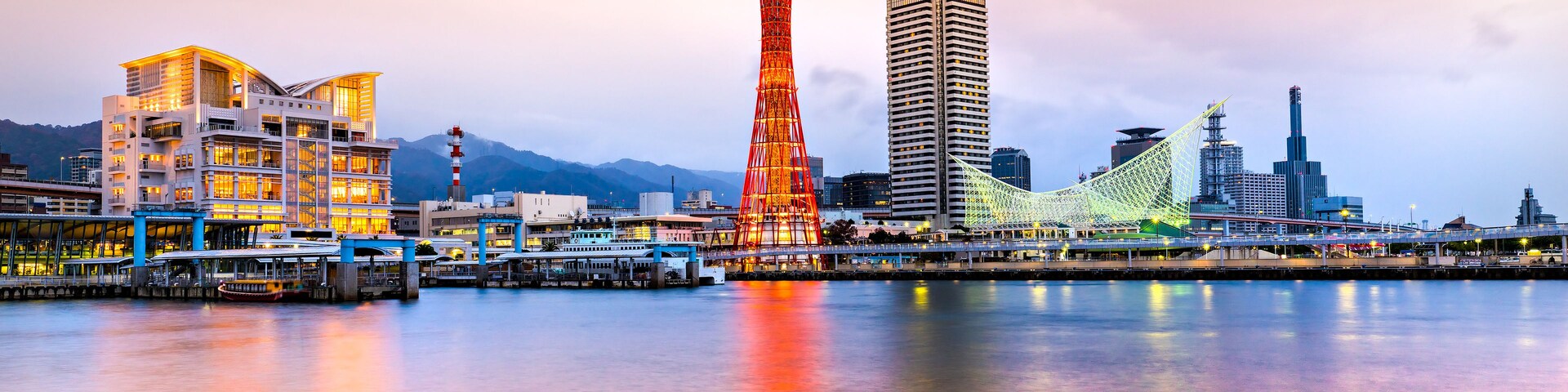 Un horizonte urbano con una torre destacada, un puente y una zona ribereña.