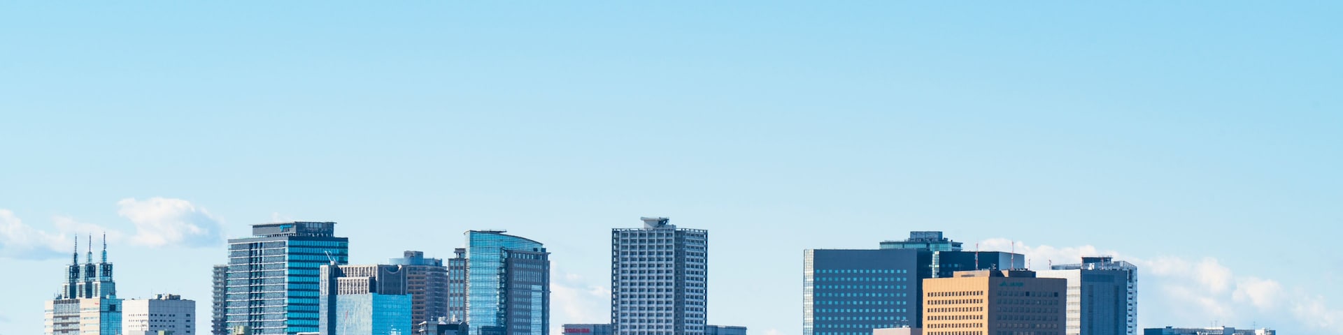 Horizonte urbano com edifícios modernos e um rio ao primeiro plano.