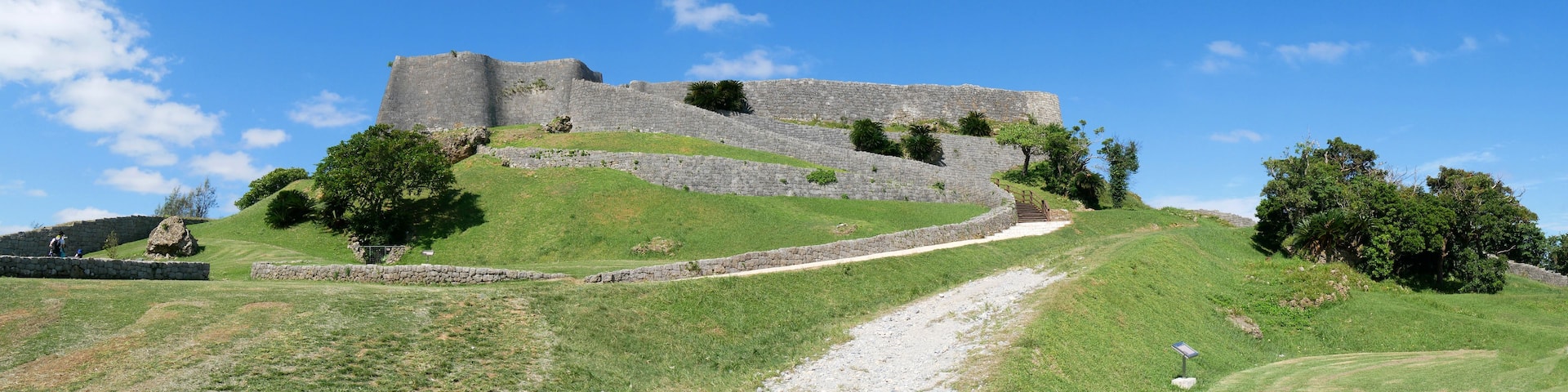 A stone fortification on a grassy hill with a clear sky.