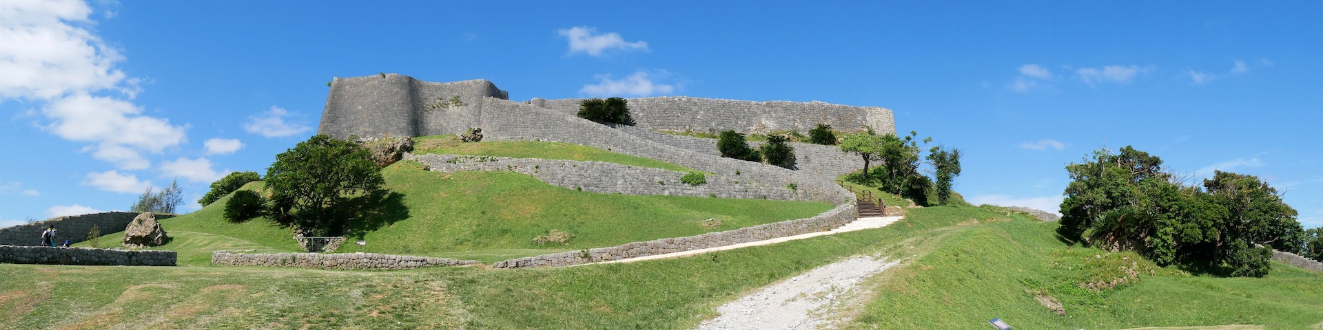 Uma fortificação de pedra numa colina coberta de relva, com céu limpo.