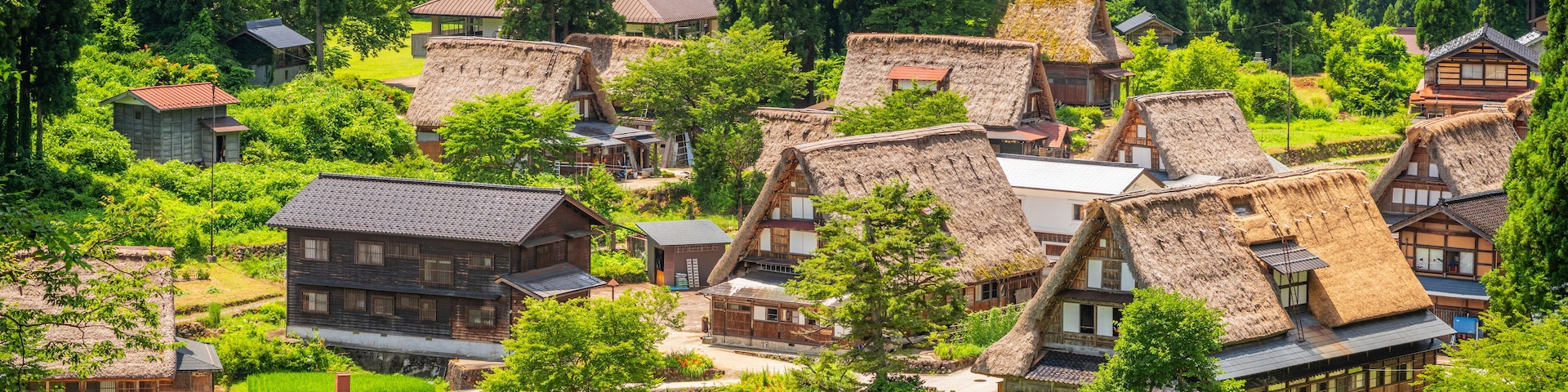 Uma aldeia com casas tradicionais de telhado de palha, rodeada por vegetação exuberante e campos em socalcos.