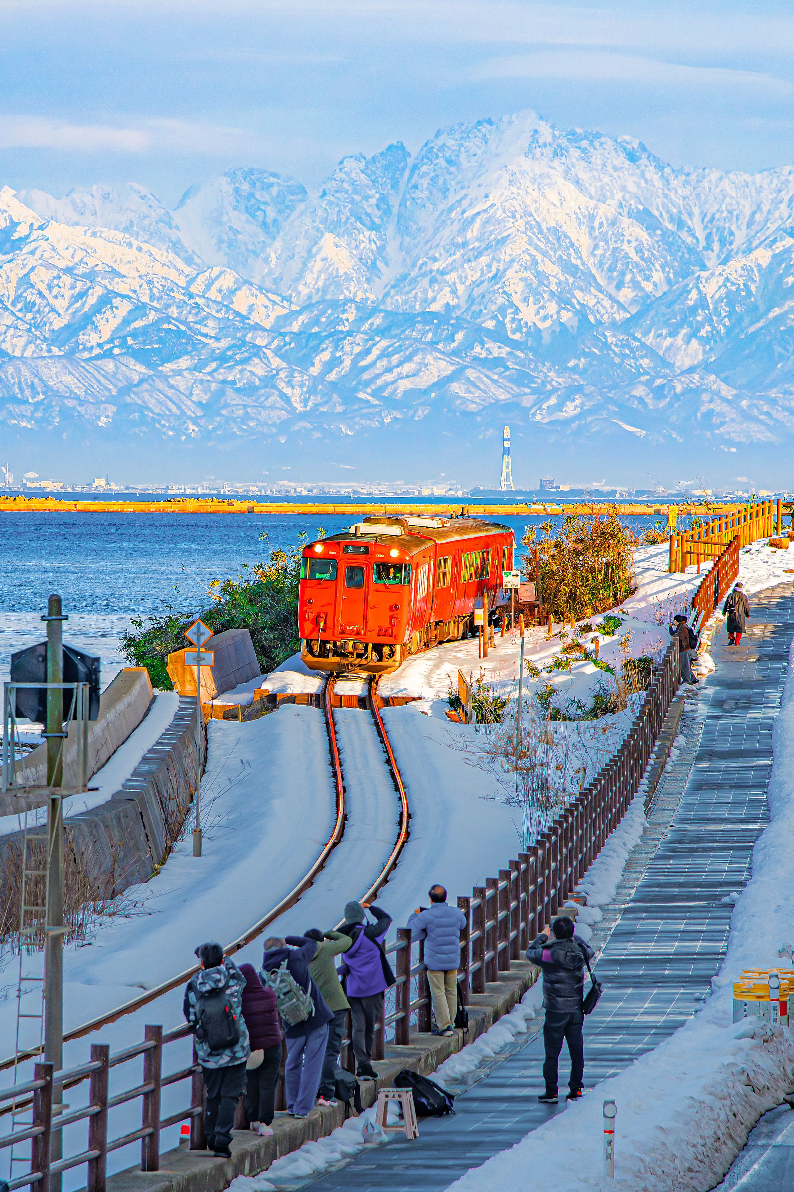 Japan - February 5, 2026 : JR Himi Line Train with Tateyama  Mountain Range of Japan Alps Background in winter, Amaharashi Kaigan Coastline, Takaoka City, Toyama, Japan