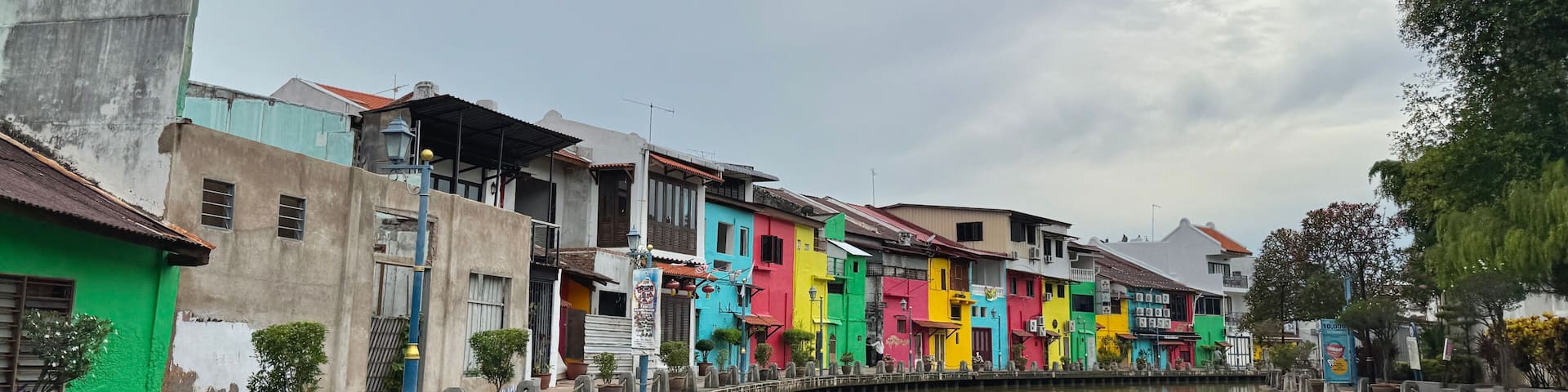 A canal with colorful buildings on one side and a bridge crossing it.