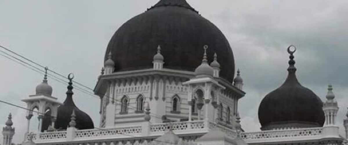 A large white mosque with multiple domes and arches.