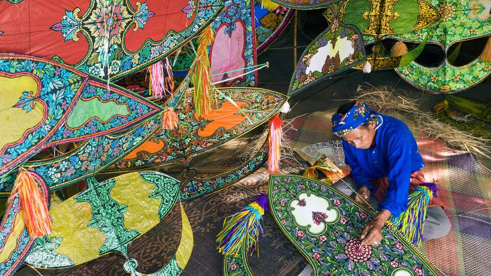 A person working on a colorful, intricately designed umbrella.