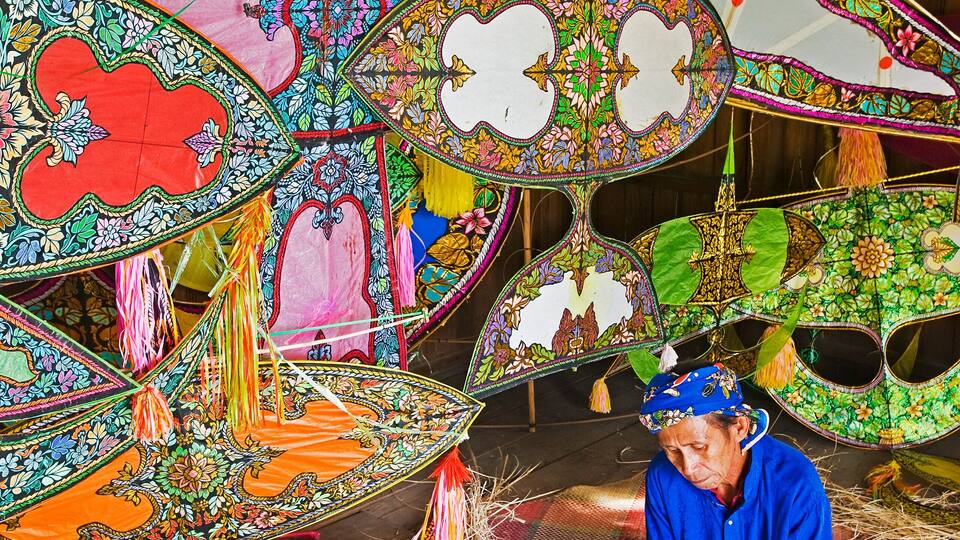 A person working on a colorful, intricately designed fabric with floral patterns and vibrant colors.