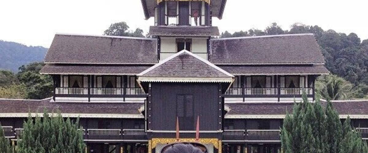 A large, traditional building with a central tower, surrounded by well-maintained gardens and trees.