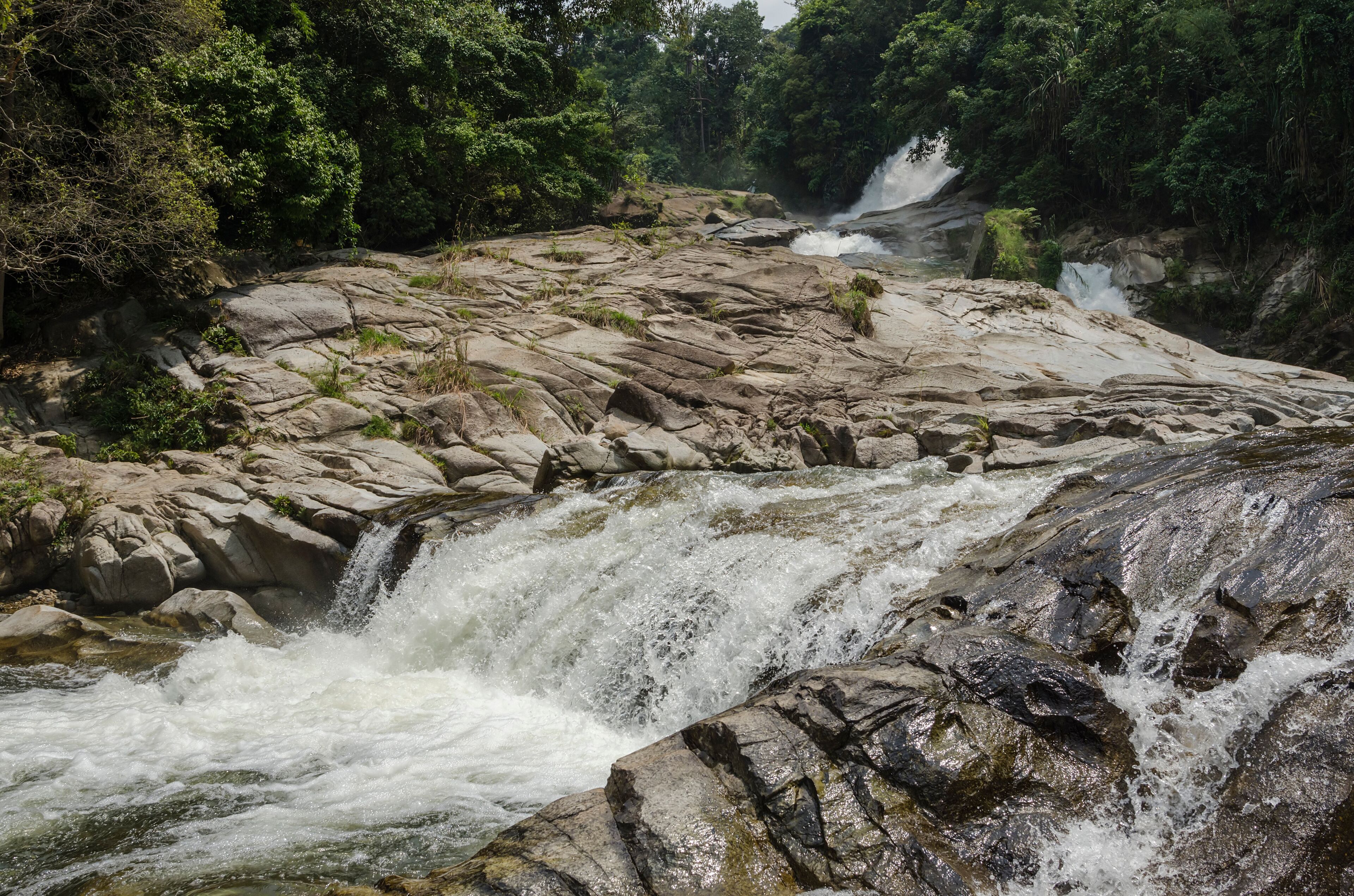 A waterfall cascading over rocky terrain surrounded by dense forest.