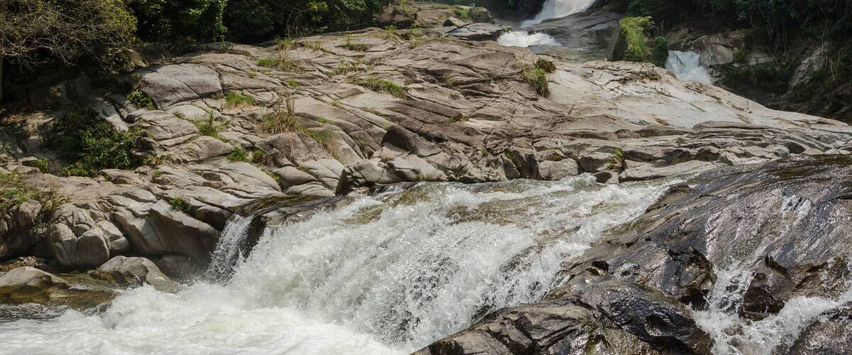 A waterfall cascading over rocky terrain surrounded by dense forest.