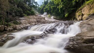 A waterfall cascading over rocks in a forested area.