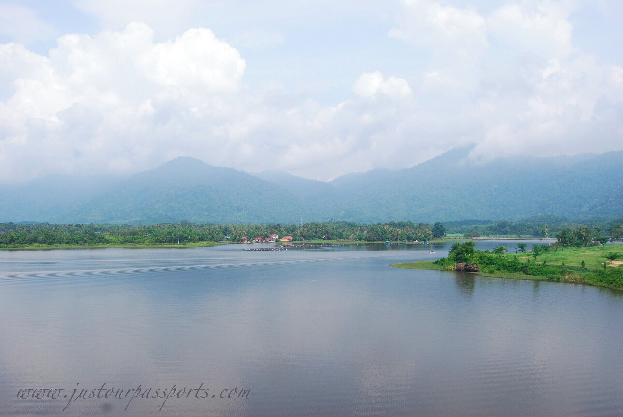 A calm lake with mountains in the background and a small village on the shore.