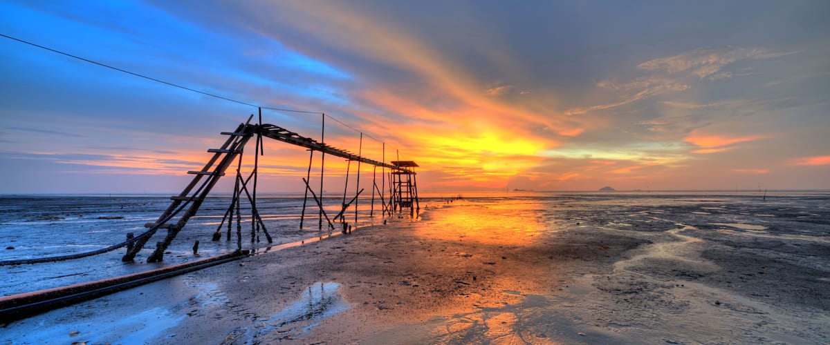 A sunset over a beach with a collapsed structure.