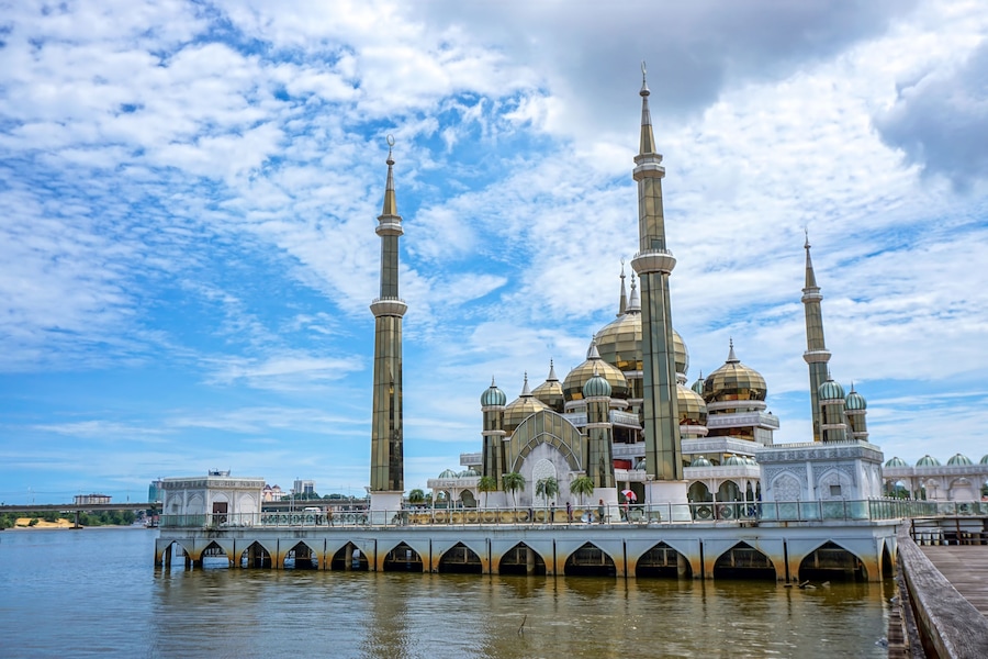 A mosque with multiple domes and minarets, a bridge over water, and a clear sky.