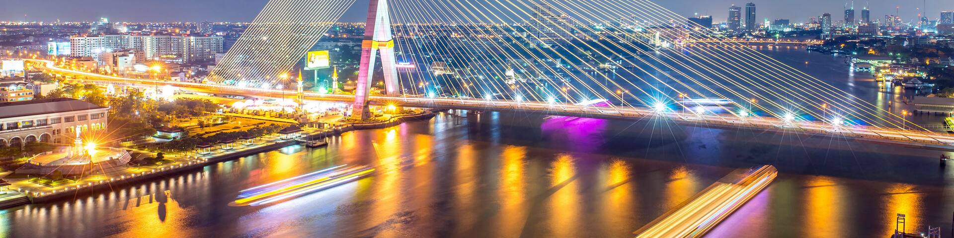 A modern bridge with a triangular design, illuminated lights, and a river below.