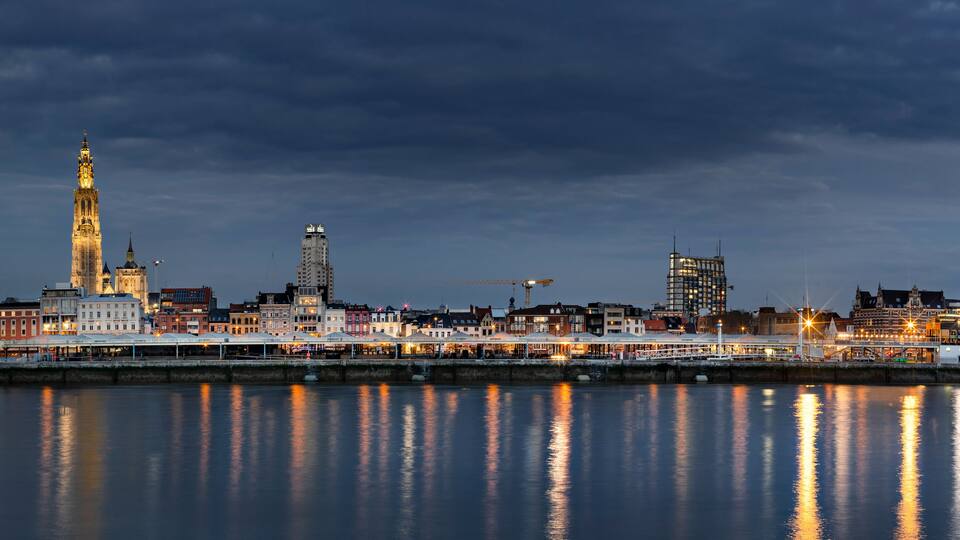 Un horizonte urbano al anochecer, con una catedral destacada y un río que refleja las luces.