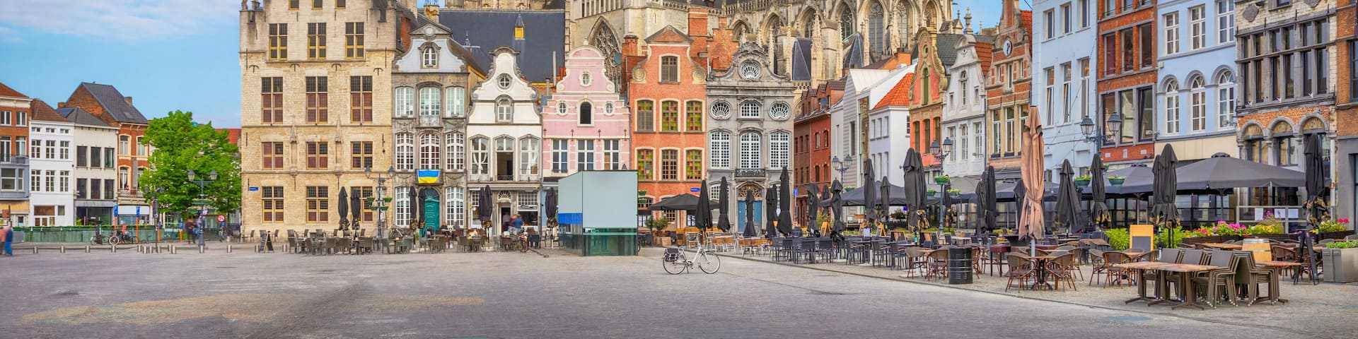 A historic cathedral with a tall spire, surrounded by colorful buildings and a cobblestone square.