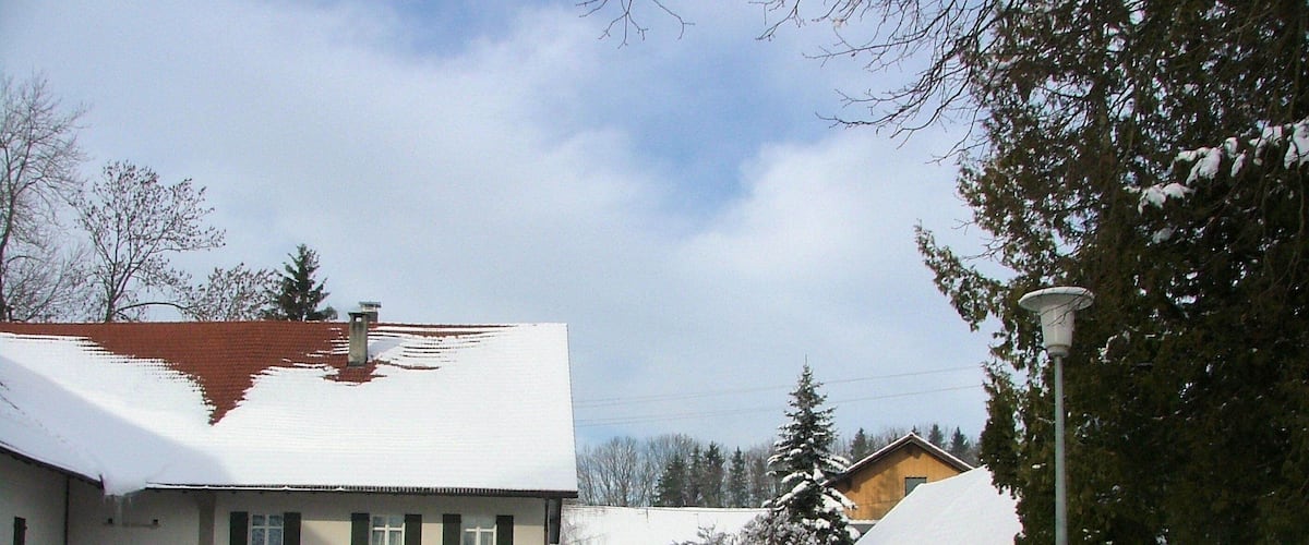 A snow-covered street with houses and a lamppost.