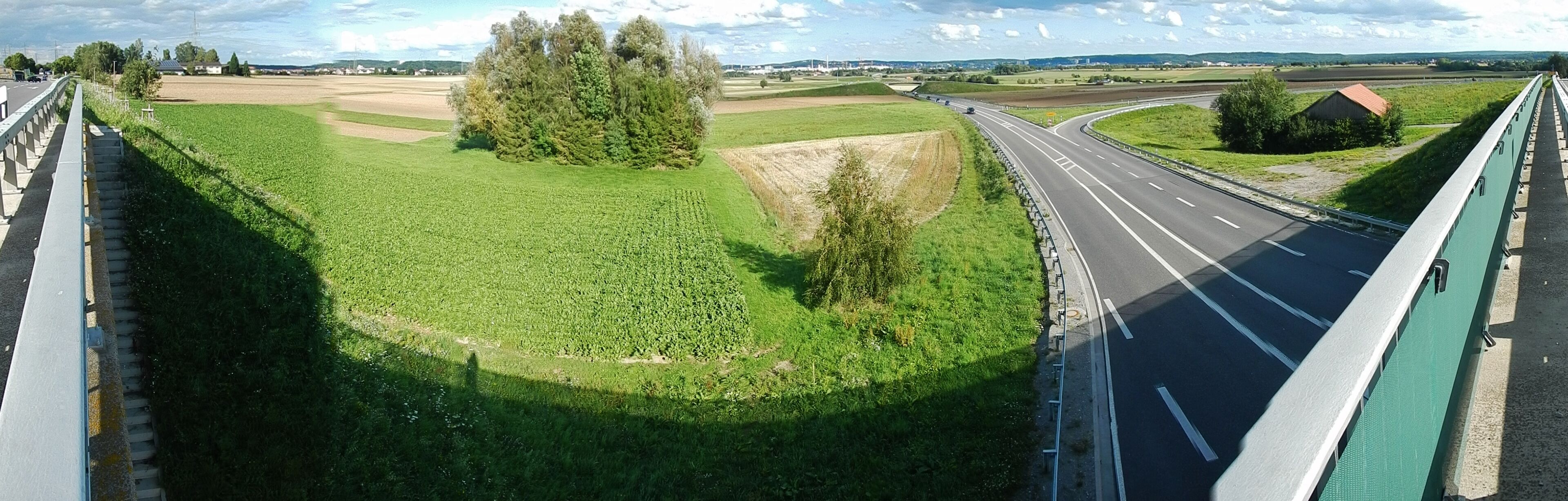 A highway curving through a rural landscape with fields and trees.