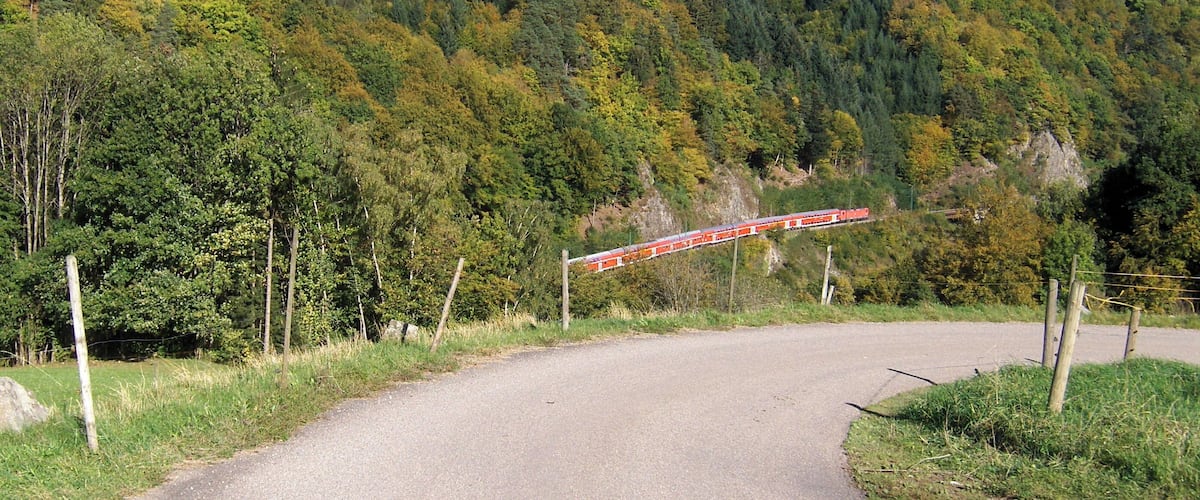 Zug von DB Regio mit 6 Doppelstockwagen und 2 Loks der Baureihe 143 auf der Fahrt ins Höllental oberhalb von Falkensteig.