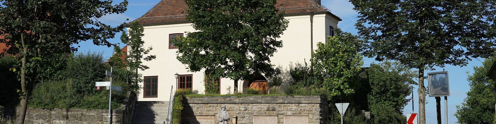 Schwäbisch Hall, Stadtteil Gailenkirchen: Blick von Westen auf die Pfarrkirche, davor das Gefallenendenkmal. Standort: auf der Waldenburger Straße.