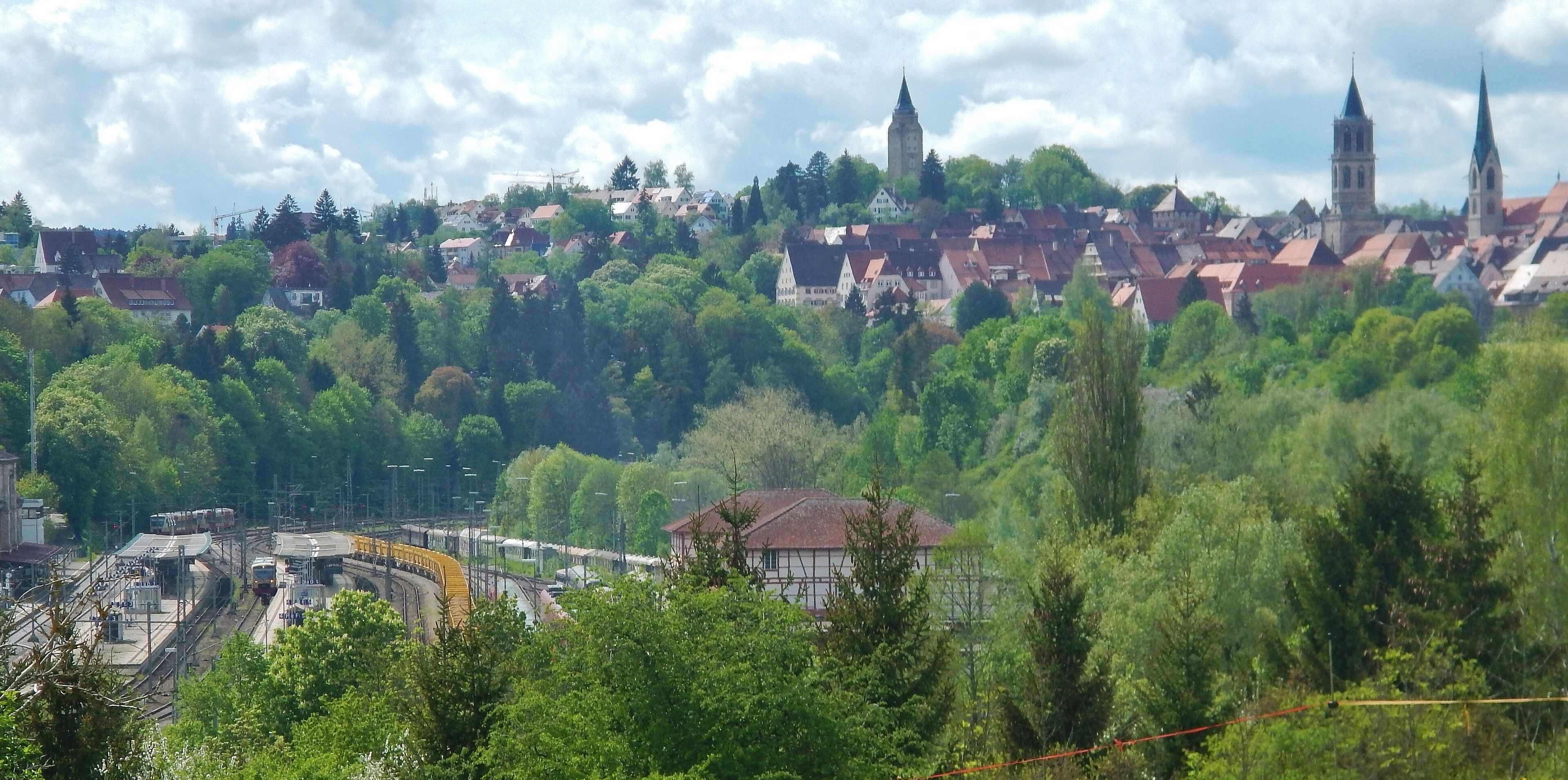 A town with historic buildings, a railway station, and a church with a tall tower.