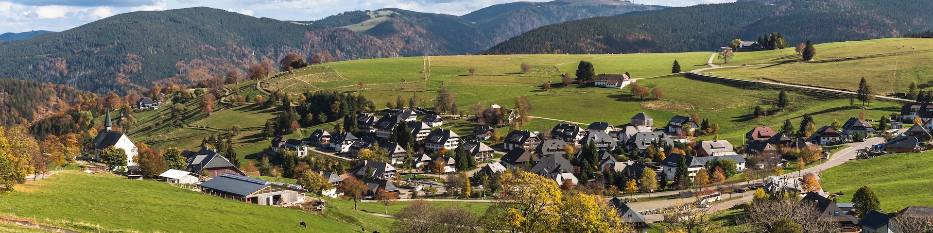 Un paysage rural caractérisé par des collines douces, un petit village et une église.