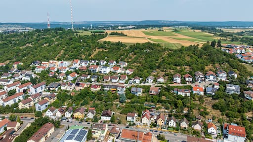 Un quartier résidentiel avec des maisons, un grand champ et une éolienne en arrière-plan.