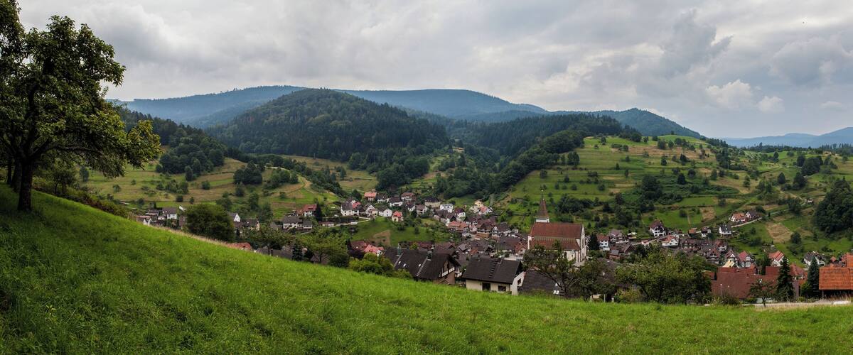 A village nestled in a valley with rolling hills and a church in the center.