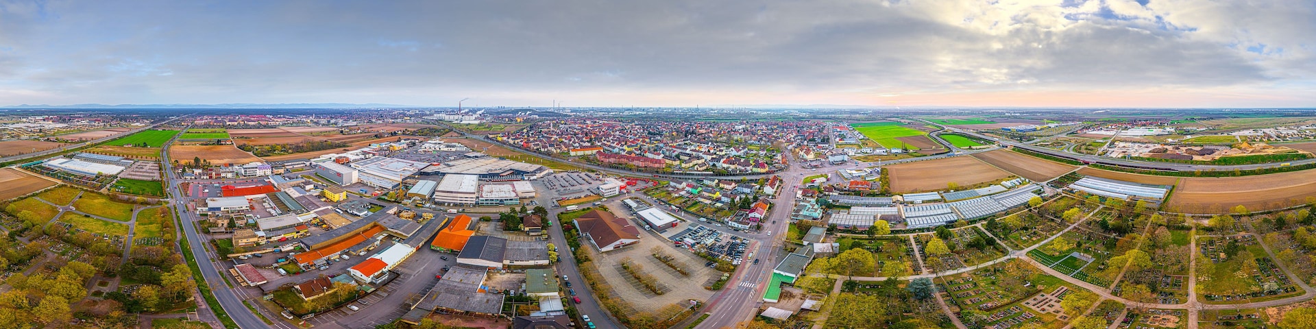Vista aérea de un pueblo con edificios industriales, carreteras y campos verdes.