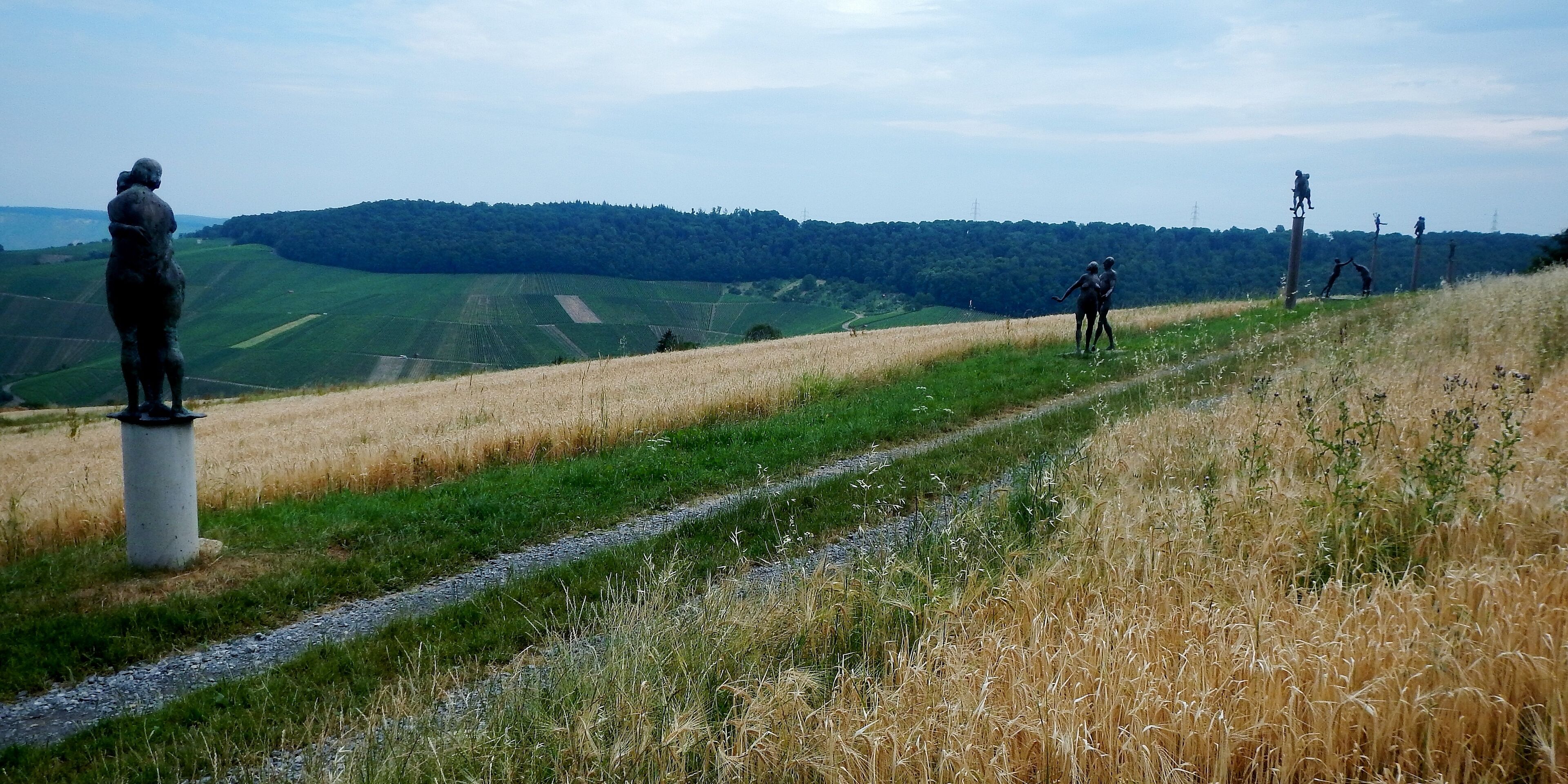 A statue on a hill, a path, and a distant forest.