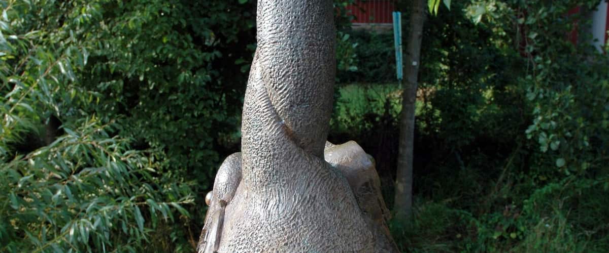 A bronze sculpture of a bird with a long neck and large eyes, surrounded by smaller bronze spheres.