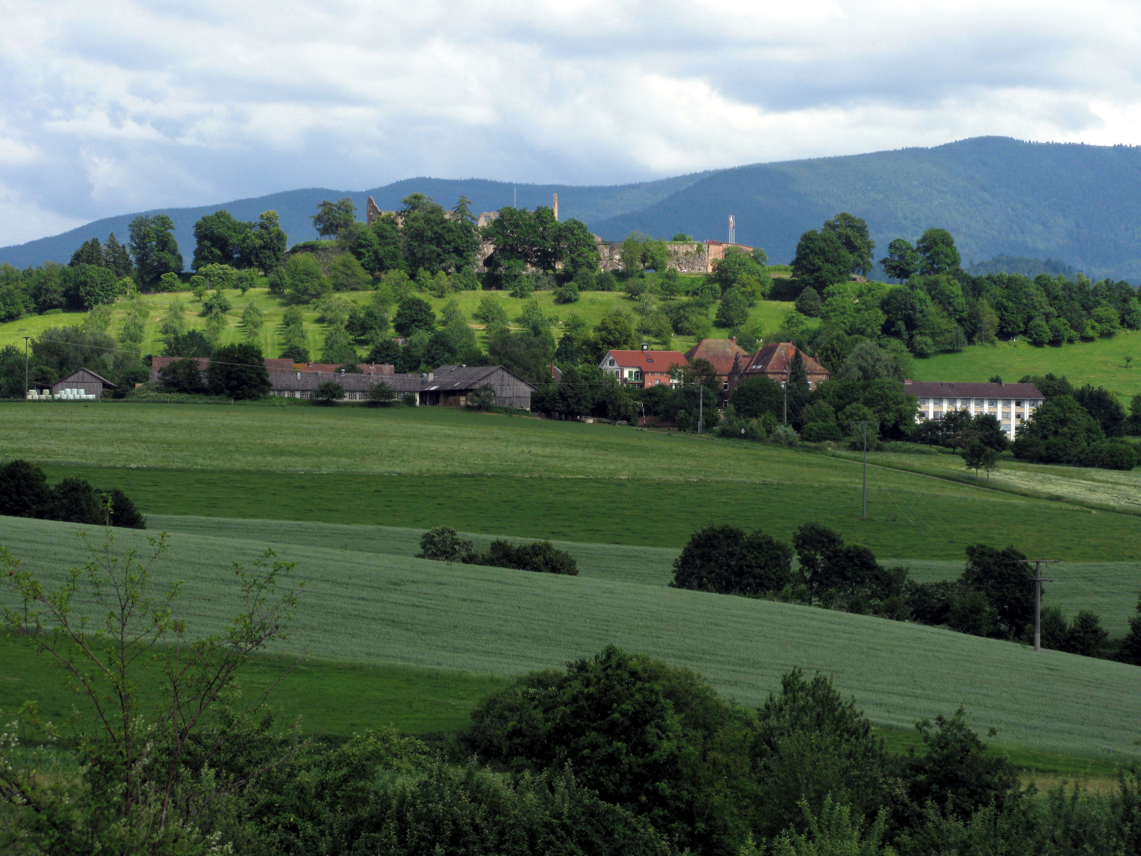 A rural landscape with rolling hills, a cluster of houses, and a prominent church steeple.