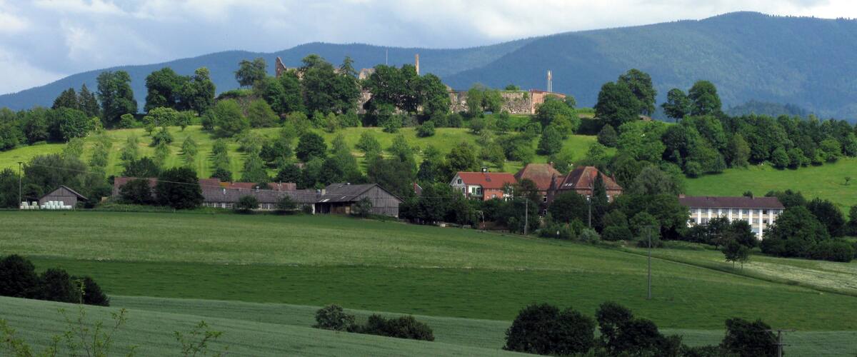 A rural landscape with rolling hills, a cluster of houses, and a prominent church steeple.