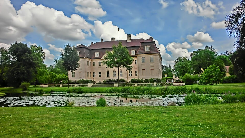 A large stately building with a pond in the foreground.
