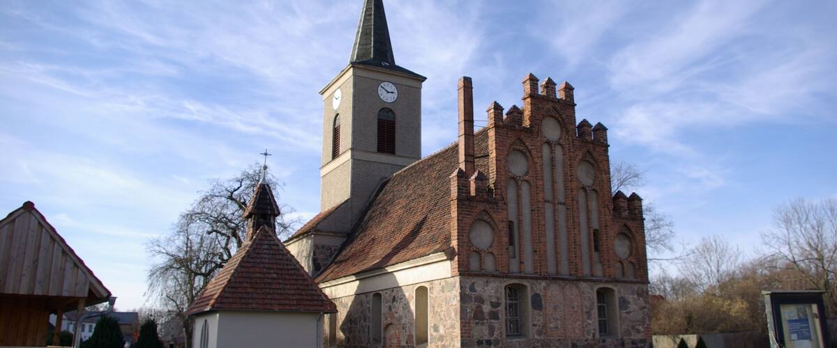 A church with a clock tower and a stone building with a pointed roof.