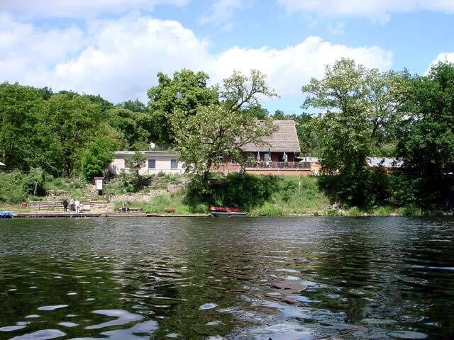 A house by a lake with trees and a dock.