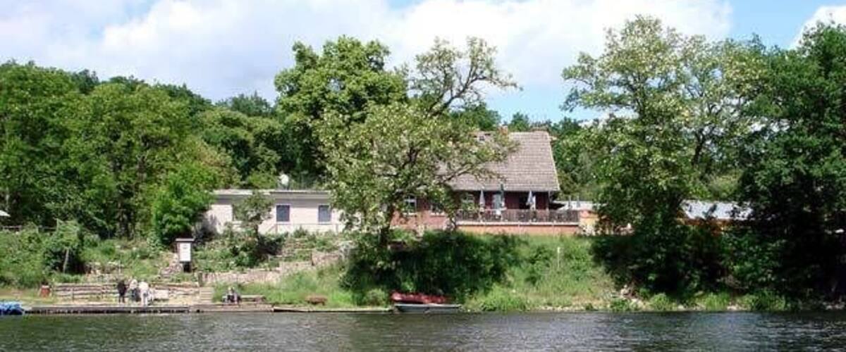 A house by a lake with trees and a dock.