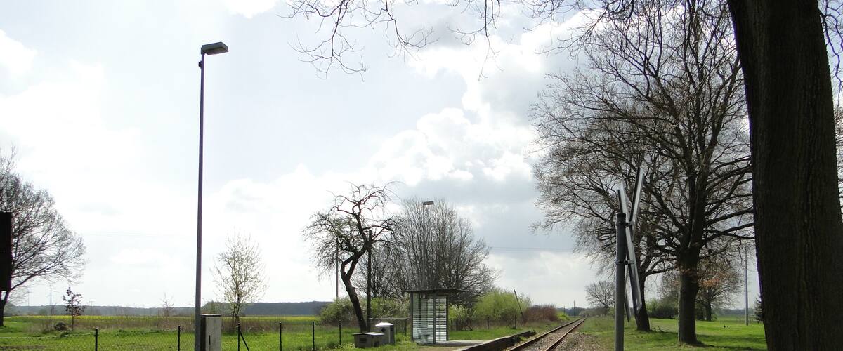 Railway tracks with a pedestrian walkway, trees, and a small shelter.
