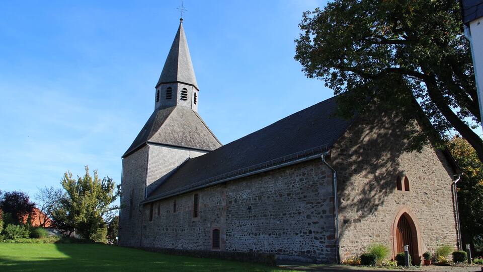 A stone church with a tall steeple and a large arched entrance.