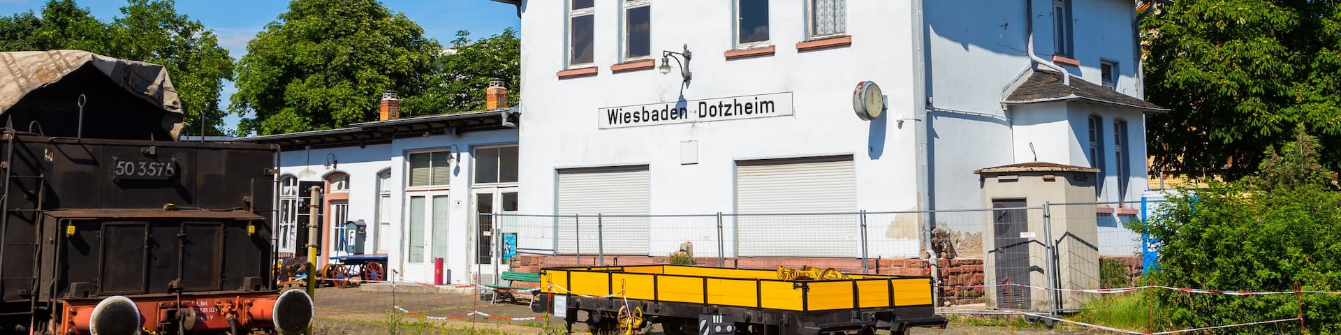 A white building with a black roof and a sign that reads 'Wiesbaden Dotzheim.'