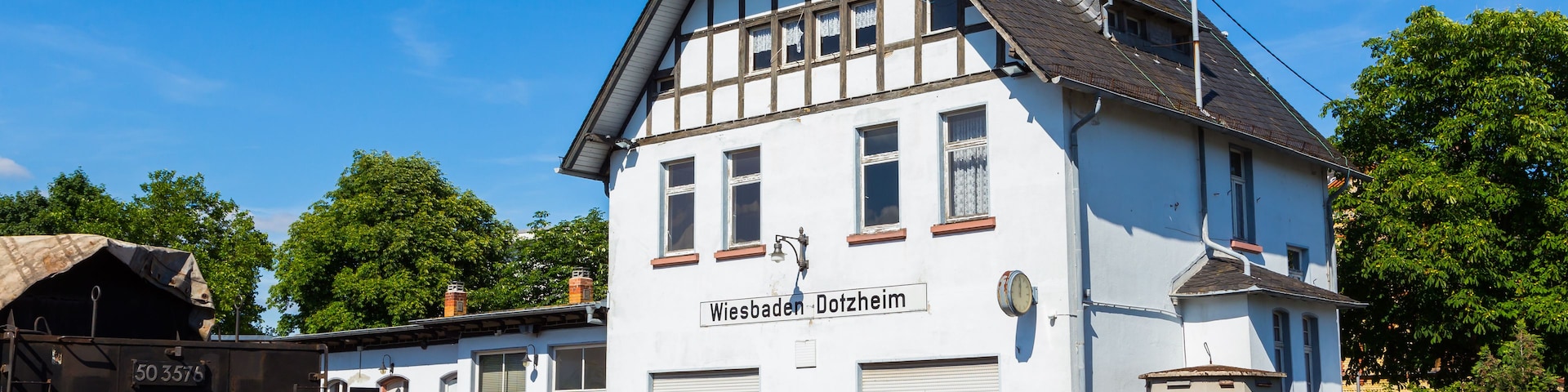 Um edifício branco com telhado preto e uma placa com a inscrição 'Wiesbaden Dotzheim'.