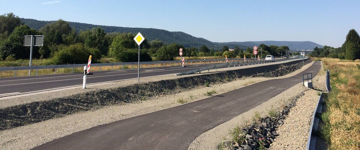 A highway with multiple lanes, speed limit signs, and a pedestrian crossing.