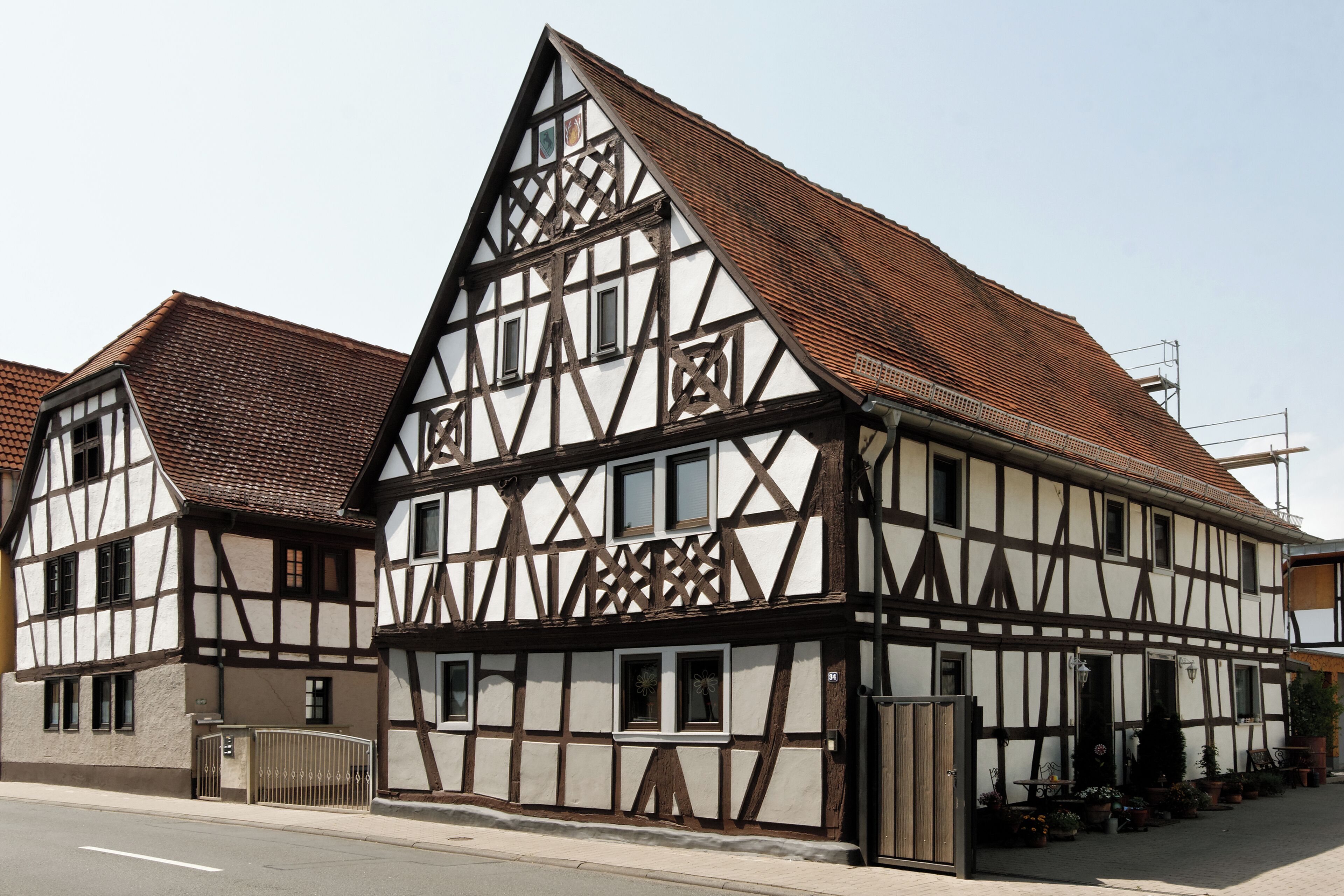 A traditional half-timbered house with a steeply pitched roof and a gated entrance.