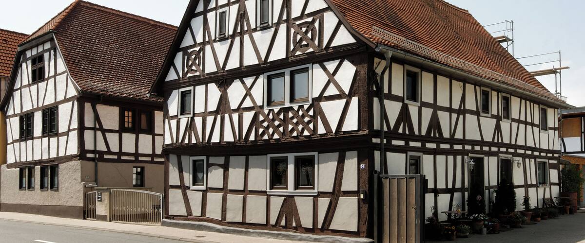 A traditional half-timbered house with a steeply pitched roof and a gated entrance.