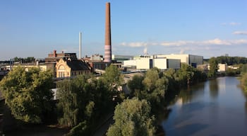 A river with industrial buildings and a tall chimney.